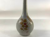 un petit vase orné d'une fleur, posé sur une surface blanche