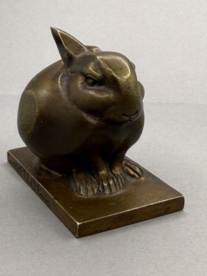 a bronze sculpture of a rabbit on a wooden base