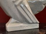 a white owl statue on a table with a red wall in the background