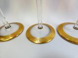 three gold plated wine glasses on a white table with a chain