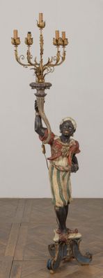 a statue of a man holding a candelier on a table