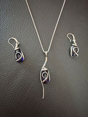 un ensemble composé d'un collier et de boucles d'oreilles en argent, posé sur un fond en cuir noir