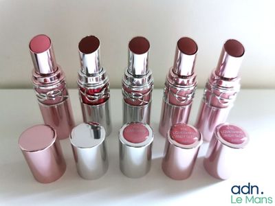 four different shades of lipstick are lined up on a white surface