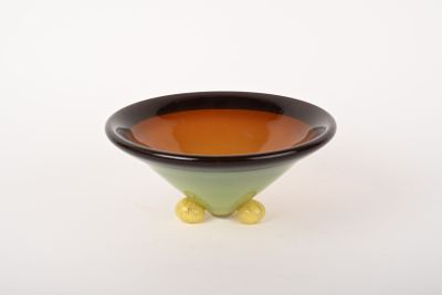 un bol noir et vert avec des pieds jaunes sur un fond blanc