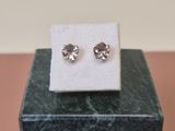 a pair of earrings sitting on top of a marble block