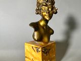 bronze bust of a woman with curly hair on a marble base