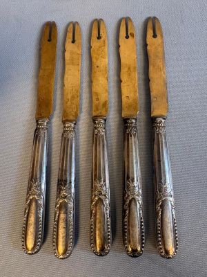 quatre fourchettes et cuillères en argent sont alignées sur une table