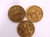 three gold coins sitting on top of each other on a white surface