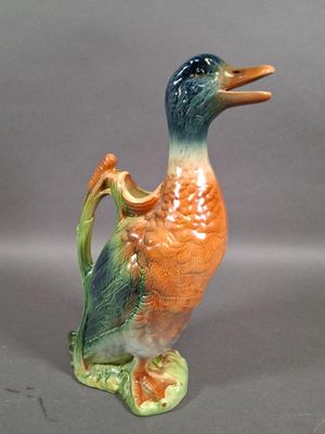 a small ceramic duck with a handle on a gray surface