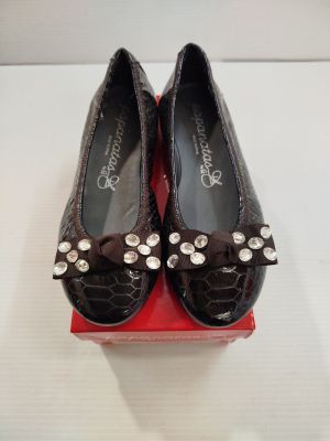 une paire de chaussures noires ornées de nœuds, posée sur une boîte rouge