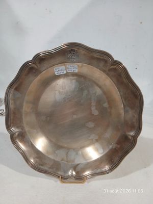 une assiette en argent antique avec une poignée sur une surface blanche