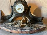 une statue représentant une femme allongée sur une dalle de marbre, avec une horloge en arrière-plan