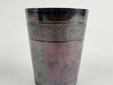 a metal cup with a pattern on it on a white surface