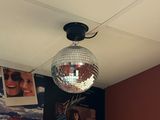 a disco ball hanging from the ceiling above a bed