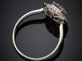 a close up view of a purple sapphire and diamond ring on a black surface