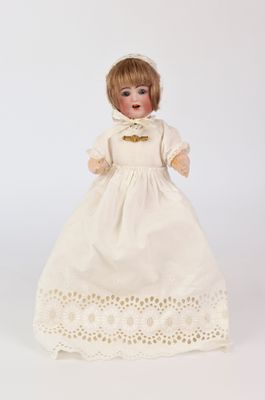 une poupée ancienne en porcelaine représentant une femme vêtue d'une robe blanche et d'un bonnet