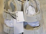 a pair of white sandals on the floor with a price tag