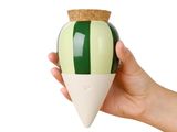 a hand holding a green and white vase with a cork top