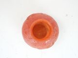 a small orange vase sitting on a white surface