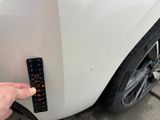 a hand that is holding a remote control in front of a car