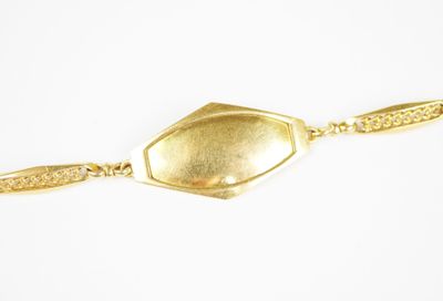 gros plan d'un bracelet en or sur une surface blanche