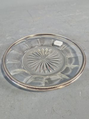une assiette en verre à bord argenté posée sur une table