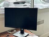 a computer monitor sitting on a desk in front of a window