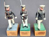 three figurines of men dressed in military uniforms