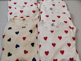 trois t-shirts ornés de cœurs, posés sur une table