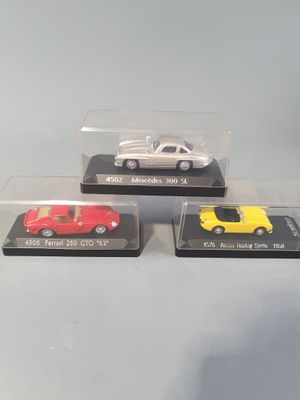 three die cast cars in plastic cases sitting on a table