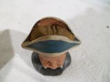 une figurine représentant un homme coiffé d'un chapeau, posée sur une table