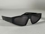 une paire de lunettes de soleil noires posée sur une surface blanche