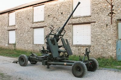 a large machine gun sitting on a cart in front of a building