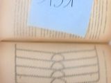 une personne tenant une feuille de papier au-dessus d'un livre ouvert