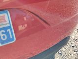 the rear end of a red car with a license plate on it