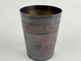 an old metal cup sitting on top of a white surface