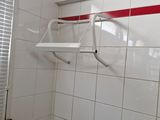 une salle de bains carrelée de blanc avec une bande rouge sur le mur