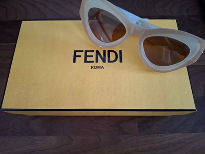 des lunettes de soleil Fendi dans un étui posé sur une table en bois