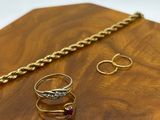 two gold rings and a chain on a wooden table