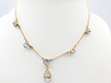 a gold necklace with blue and white crystals on a mannequin