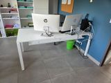 un bureau blanc sur lequel sont posés deux ordinateurs, dans une pièce