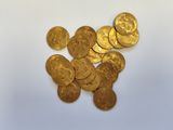 a close up of a pile of gold coins on a white surface