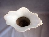 a white vase with a hole in it on a table