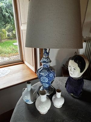 une table sur laquelle se trouvent une lampe, des vases et une figurine