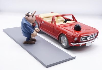 a figurine of a man standing next to a red car