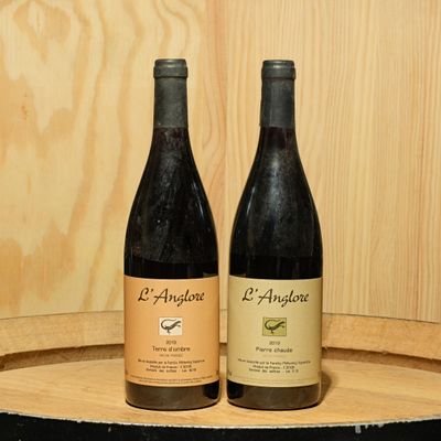 two bottles of wine sitting on top of a barrel next to each other