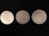 three silver coins sitting next to each other on a black surface