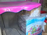 un parapluie rose posé sur un réfrigérateur, à côté de cartons