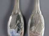 two spoons that are sitting side by side on a table