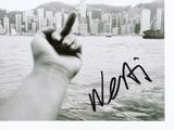 signed photograph of a hand holding a cell phone in front of a cityscape